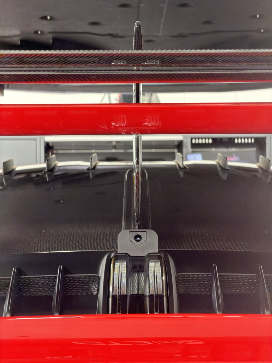 Housing on the car's centreline, tucked beneath the Manthey fin — clean rearward view, clean cable routing.